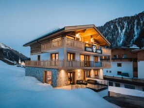 Un chalet à deux étages doté d’un balcon, d’une façade en pierre et d’une enseigne indiquant qu’il s’agit d’un chalet.