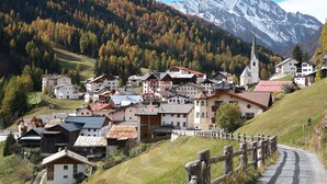 A mountain village with traditional wooden houses, a church, and a snow-capped mountain in the background. - Avero Lodge by MEIN SAMNAUN – MOUNTAIN HOMES, (Samnaun-Compatsch) by Interhome (Samnaun)