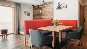 A modern dining area with a wooden table, two grey chairs, a red bench, and a wooden wall with a skull decoration. - Avero Lodge by MEIN SAMNAUN – MOUNTAIN HOMES, (Samnaun-Compatsch) by Interhome (Samnaun)