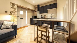 A modern kitchen with dark cabinets, a marble backsplash, and a bar stool.