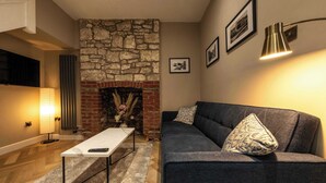 A living room with a stone fireplace, a sofa, a coffee table, and a lamp.