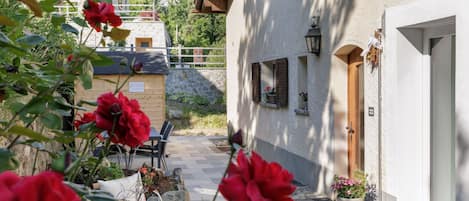 Un patio con un camino de piedra, un banco de madera y una puerta a un edificio.