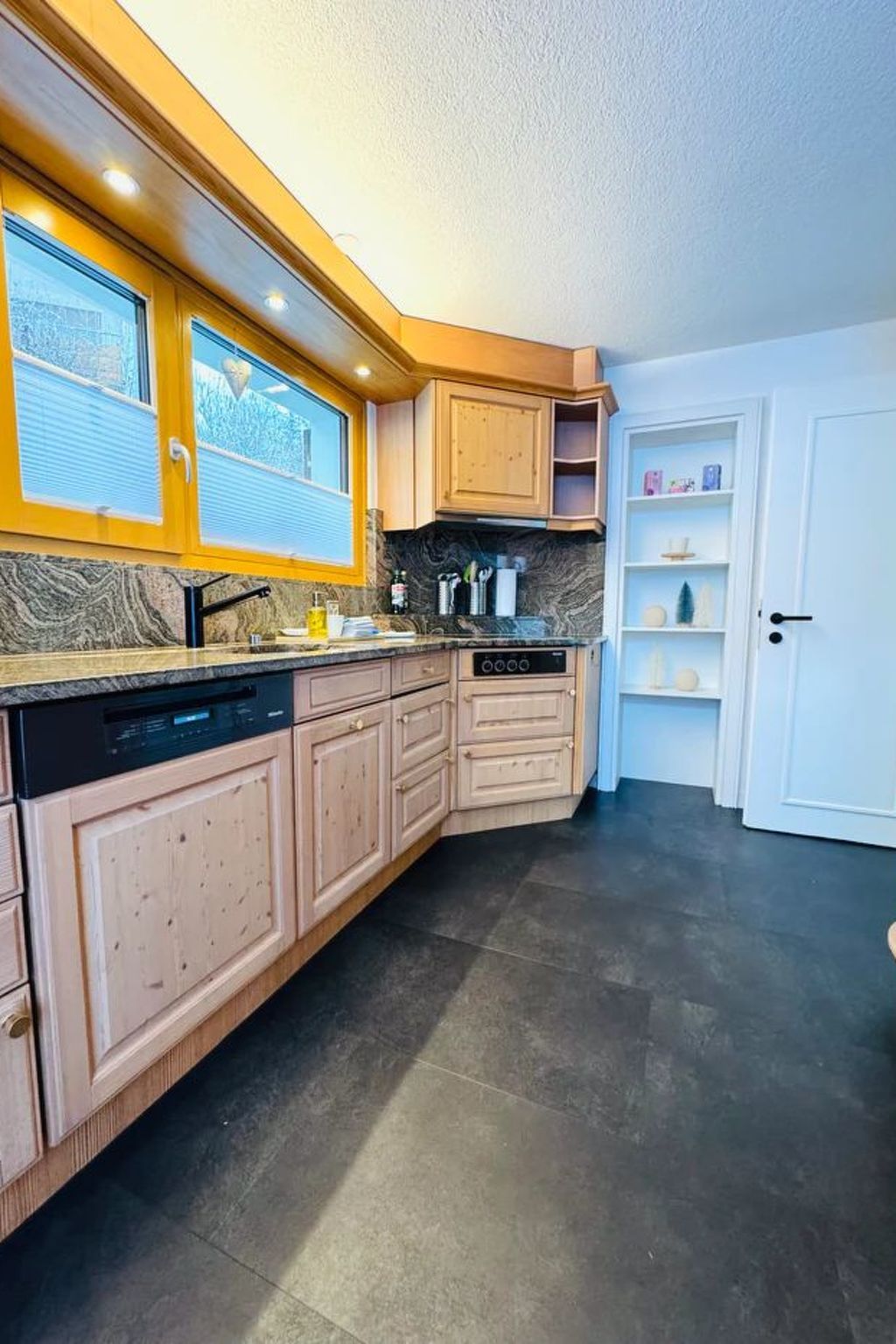 Une cuisine avec des meubles de rangement en bois, un lave-vaisselle et une cuisinière.