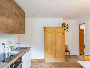 A kitchen with wooden cabinets, a stove, and a sink. - Chasa Savü, (Guarda) by Interhome (Guarda)