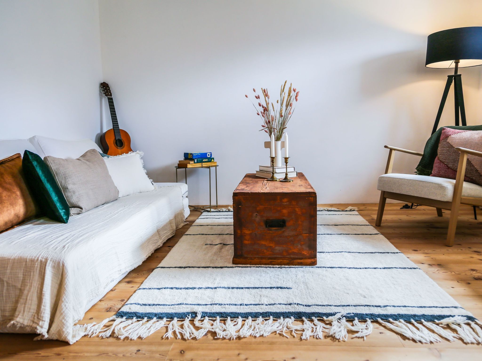 Un salon avec un canapé, une table basse, une guitare, une lampe et un fauteuil.