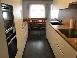 A compact kitchen with a dining area, a built-in oven, and a sink. - Suravia 56, (Müstair) by Interhome (Müstair)