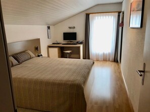A bedroom with a large bed, a desk with a computer, and a window with curtains. - Suravia 56, (Müstair) by Interhome (Müstair)