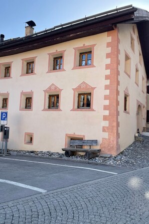 Ein Gebäude mit vielen Fenstern, einem Parkschild und einer gepflasterten Fläche mit Steinen.
