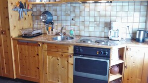 Cuina amb armaris de fusta, rentaplats, fogó i cafetera.