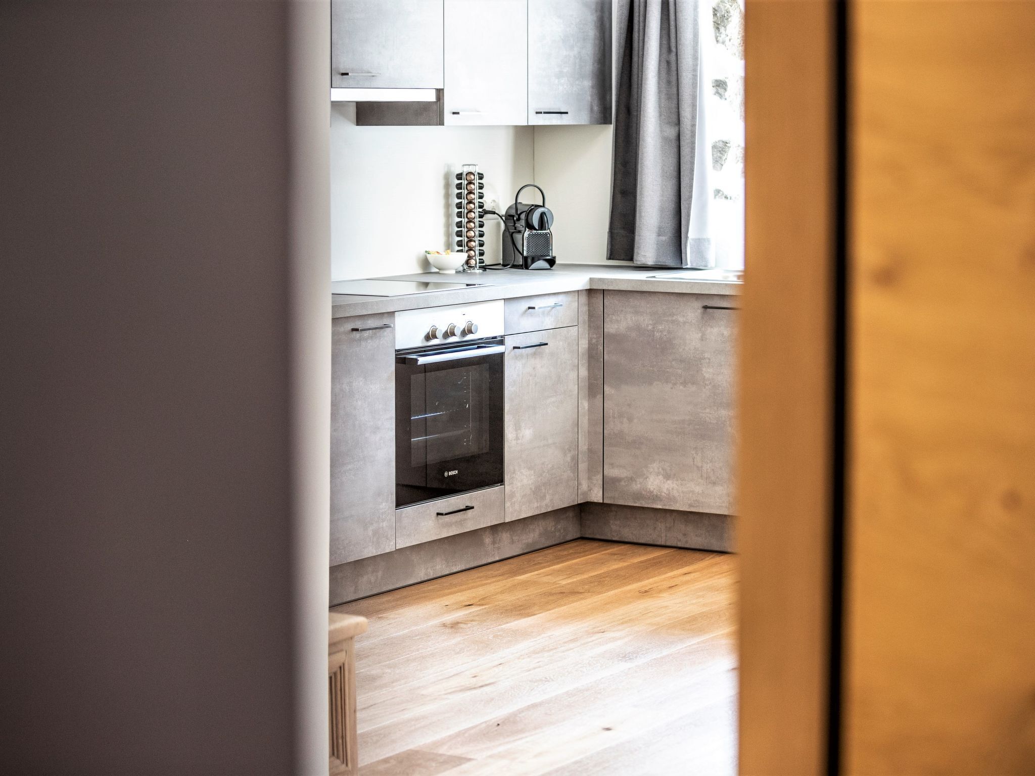 Cocina compacta con horno integrado, hervidor y cafetera sobre la encimera.
