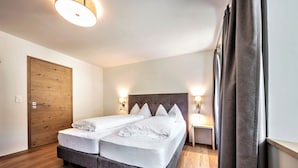 Un lit double avec une tête de lit, deux tables de chevet avec des lampes, une armoire en bois et un rideau.
