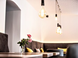 Um interior moderno com área de estar, um vaso com flores e luminárias pendentes.