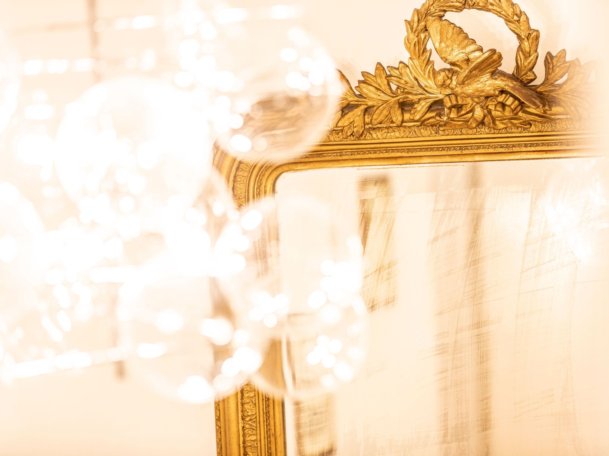 Un miroir à cadre doré, orné d’un motif décoratif en partie supérieure.