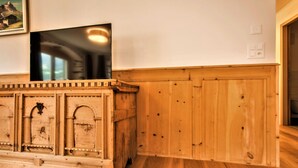 Un meuble en bois sur lequel est posée une télévision, un tableau encadré accroché au mur et un plancher en bois.