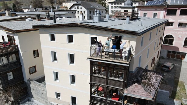 Un edificio de varios pisos con balcones, un patio central y vistas de edificios circundantes.
