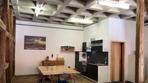 Eine kleine Küche mit Esstisch und Stühlen, einem Bild an der Wand und Holzdielen.