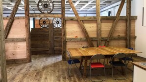 Ein rustikaler Holzraum mit Tisch und Stühlen, Holzbalken und Rädern an der Decke.