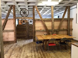 A rustic wooden room with a table and chairs, wooden beams, and wheels on the ceiling. - Ferienwohnungen Paclerahof, (Sta. Maria - Santa Maria Val Müstair) by Interhome (Sta. Maria GR)
