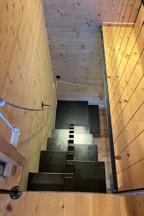 Un escalier en bois avec des rampes en métal et une main courante en corde.
