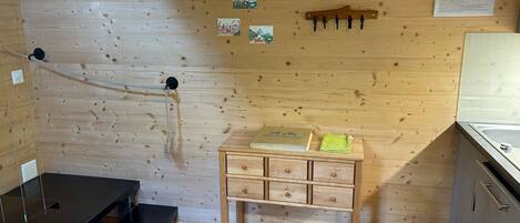 Une pièce en bois avec une petite table en bois, un banc en métal et une corde fixée au mur.