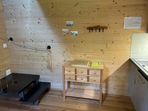 Une pièce en bois avec une petite table en bois, un banc en métal et une corde fixée au mur.