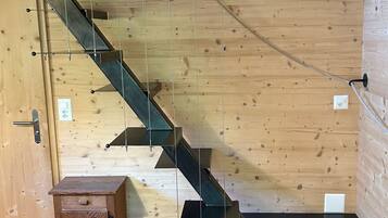 A wooden staircase with a metal handrail, a small wooden cabinet, and a black platform at the bottom.