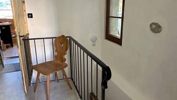 Eine Treppe mit Handlauf, ein Holzstuhl und ein Fenster mit Aussicht.