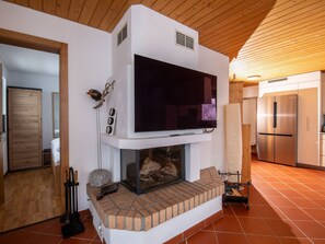 A modern kitchen with a built-in fireplace, a large flat-screen TV above it, and a stainless steel refrigerator. - Tschopp, (Samnaun-Compatsch) by Interhome (Samnaun)