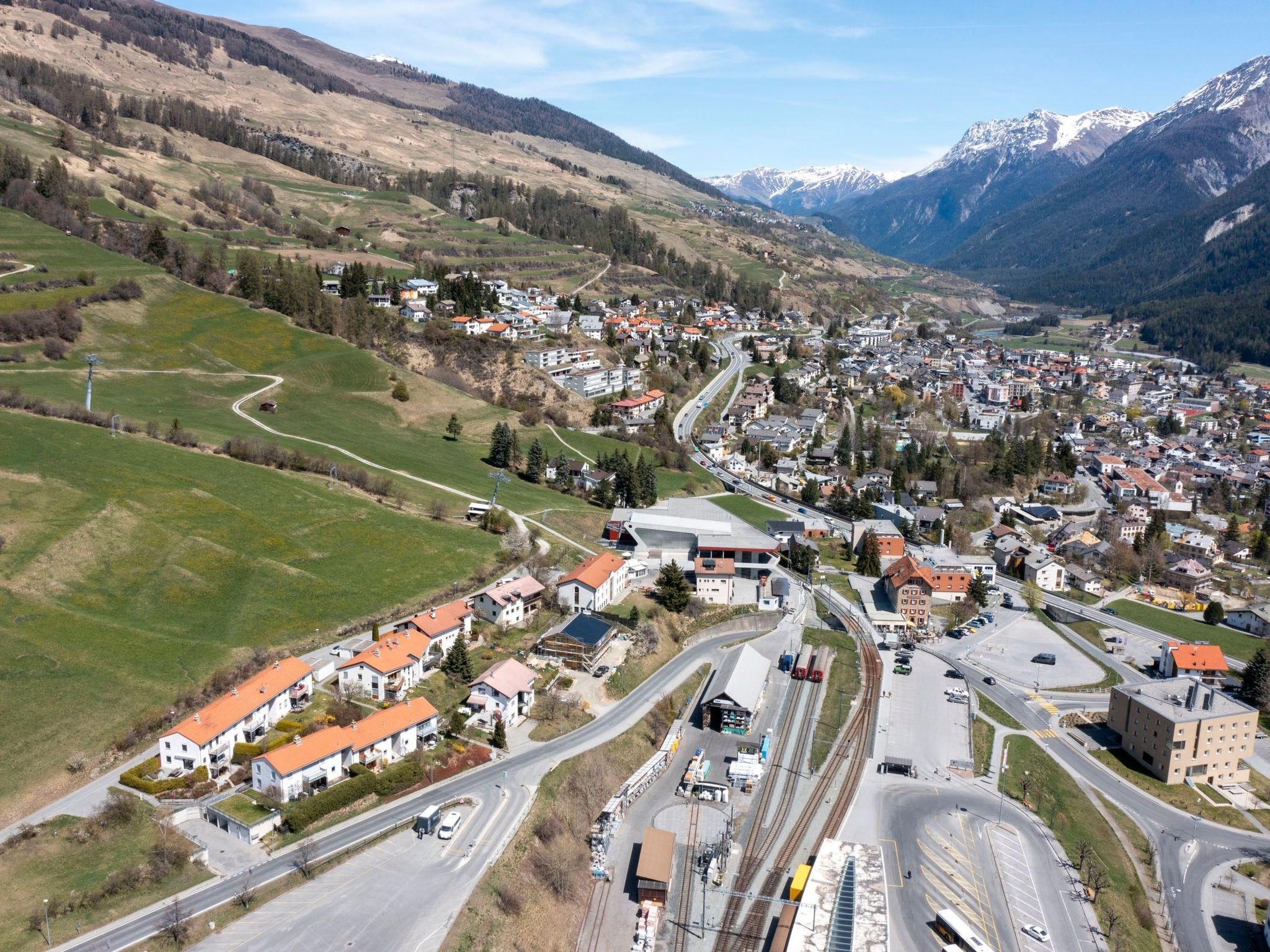 Una cittadina con una rotonda centrale, circondata da edifici residenziali e una stazione ferroviaria.