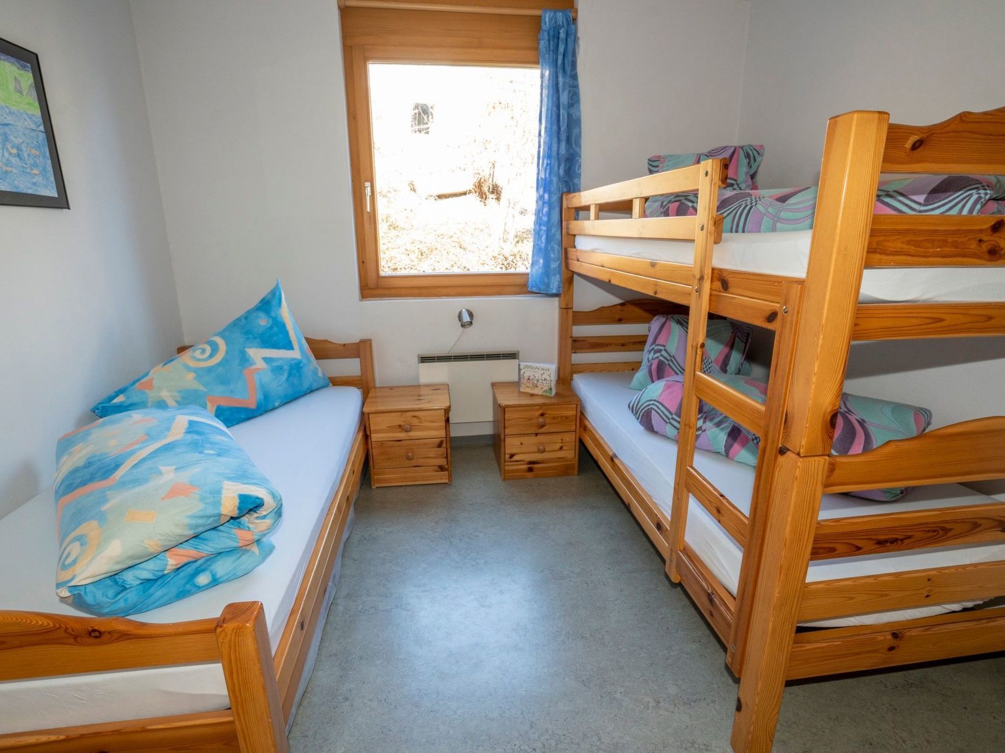A bunk bed room with a window, a small table, and a sofa.