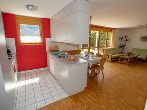 A compact kitchen with a dining area, wooden flooring, and a view of the outdoors.