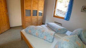 Ein Schlafzimmer mit einem Bett, einem Kleiderschrank und einem fenster mit Vorhängen.