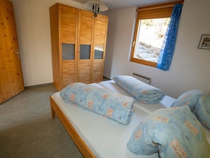 A bedroom with a bed, a wardrobe, and a window with curtains.