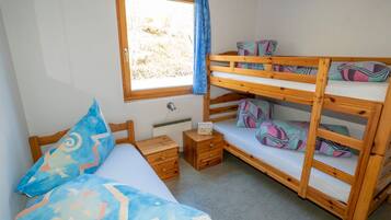 A bunk bed room with a window, a bedside table, and a bed with patterned pillows.