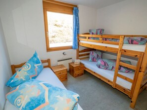 A bunk bed room with a window, a bedside table, and a bed with patterned pillows. - Senda, (Scuol) by Interhome (Scuol)