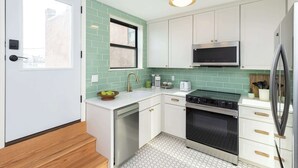 Una cocina moderna con armarios blancos, un horno de acero inoxidable y un microondas.