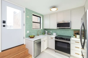 A modern kitchen with white cabinets, a stainless steel oven, and a microwave.