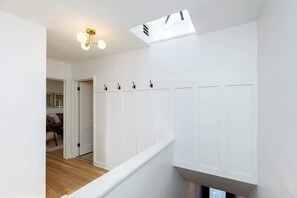 A staircase with white walls, a wooden floor, and a ceiling light fixture.