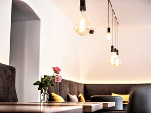 Een modern interieur met een zithoek, een vaas met een bloem en hangende lampen.