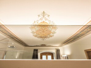 Een badkamer met een decoratief plafond, een douche en een raam met gordijnen.