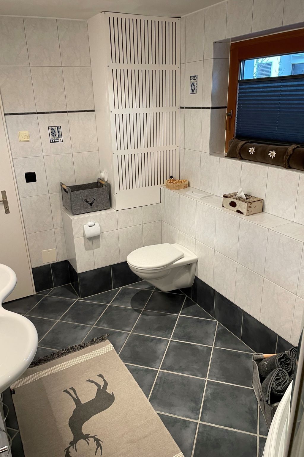 Une salle de bain avec des toilettes, un lavabo et une fenêtre.