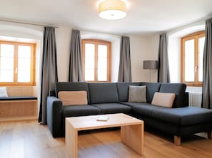 Ein modernes Wohnzimmer mit einem Ecksofa, einem kleinen Holztisch und einer Stehlampe.