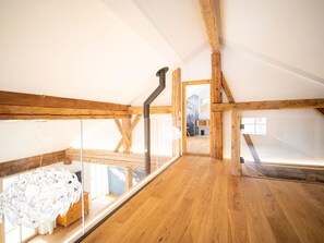 A high-ceilinged attic room with exposed wooden beams, a glass enclosure, and a visible chimney. - Chasa Muntanella, (Ftan) by Interhome (Ftan)