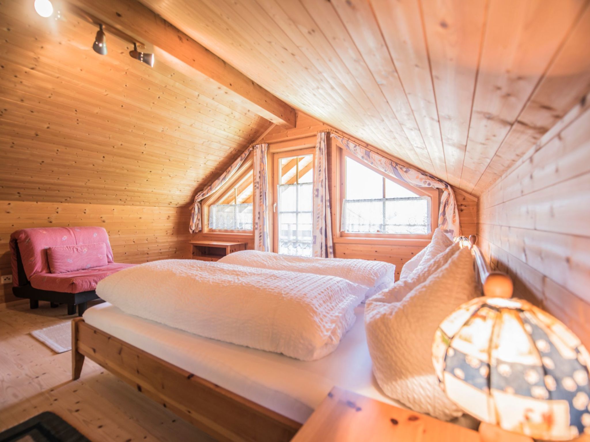 Un dormitorio acogedor con cabaña de madera, una cama, una silla y una lámpara.