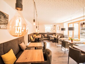 A modern interior with a seating area, tables, and hanging light fixtures.