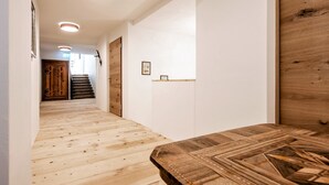 Ein Flur mit Holzboden, einer Holztür und einer Treppe, die in ein weiteres Zimmer führt.