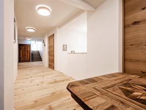 Een hal met houten vloer, een houten deur en een trap die naar een andere kamer leidt.