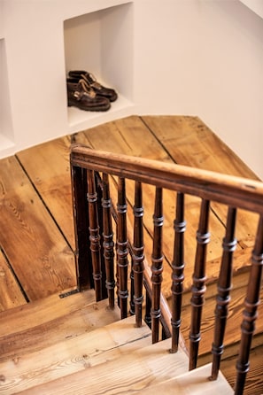 Una escalera de madera con barandilla y una pared blanca arriba.