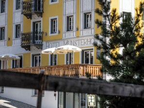 Un hotel con fachada amarilla, balcones con barandillas negras y sombrillas con la marca Coca-Cola.