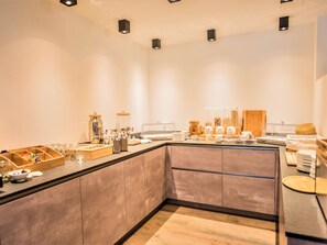 Een moderne ontbijtbalk met diverse etens- en drinkmogelijkheden, waaronder potten, kommen en een koffieapparaat.
